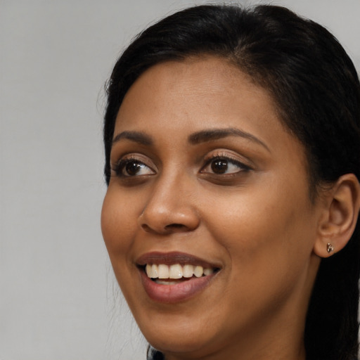 Joyful black young-adult female with long  black hair and brown eyes