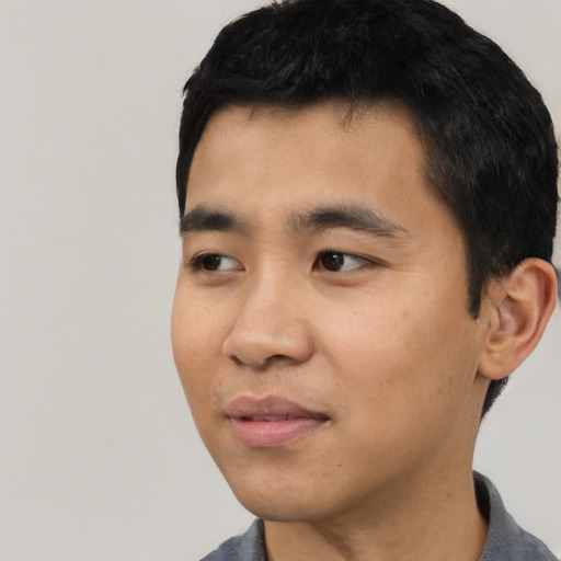 Joyful asian young-adult male with short  black hair and brown eyes