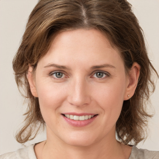 Joyful white young-adult female with medium  brown hair and grey eyes