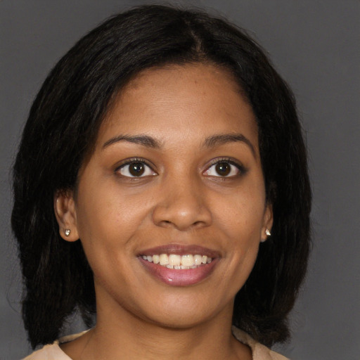 Joyful black young-adult female with long  brown hair and brown eyes