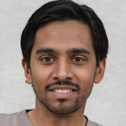 Joyful latino young-adult male with short  black hair and brown eyes