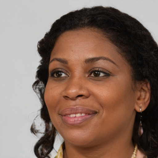 Joyful black adult female with long  brown hair and brown eyes