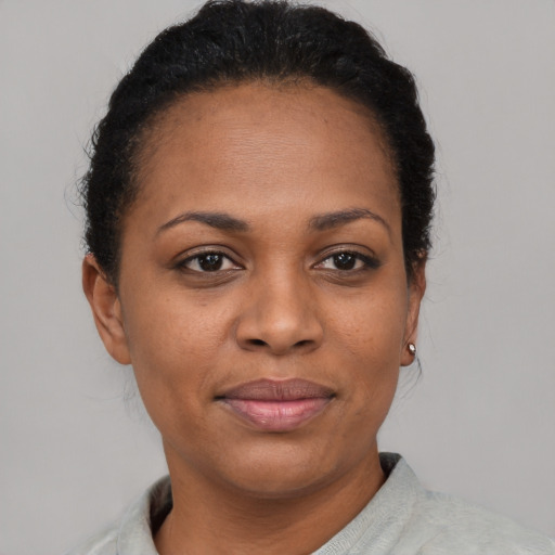Joyful black young-adult female with short  black hair and brown eyes
