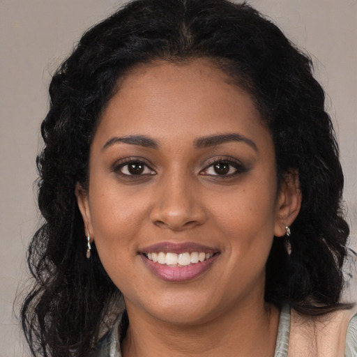 Joyful black young-adult female with long  brown hair and brown eyes