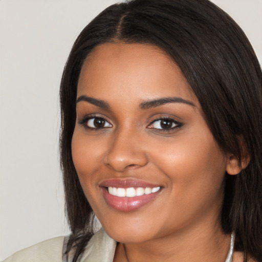 Joyful black young-adult female with long  black hair and brown eyes