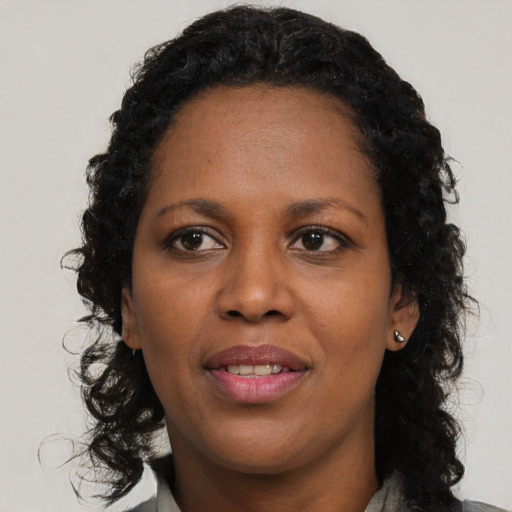 Joyful black adult female with long  brown hair and brown eyes