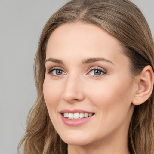 Joyful white young-adult female with long  brown hair and blue eyes