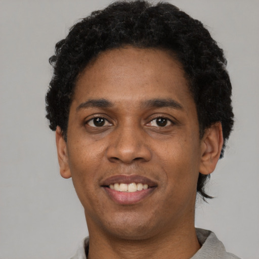 Joyful black adult male with short  black hair and brown eyes