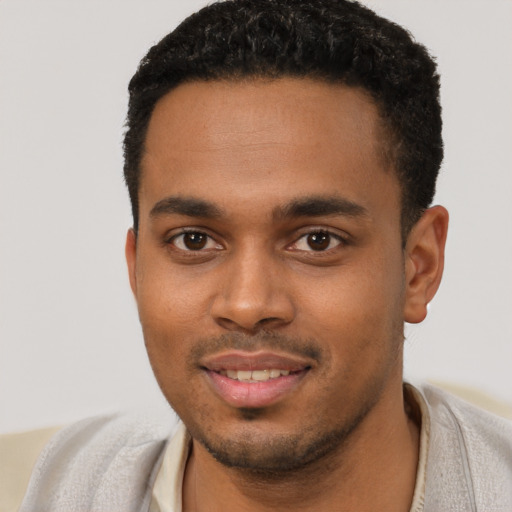 Joyful black young-adult male with short  black hair and brown eyes