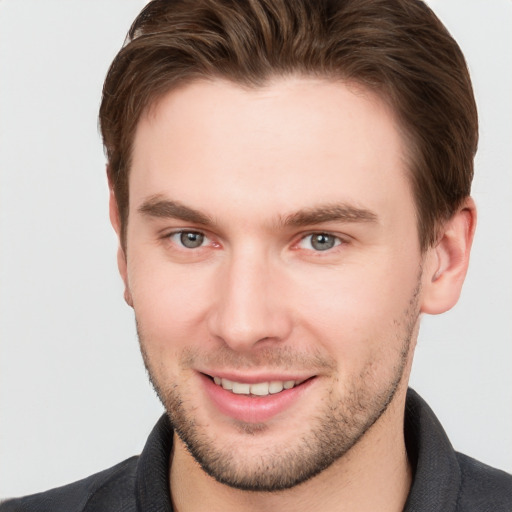 Joyful white young-adult male with short  brown hair and grey eyes