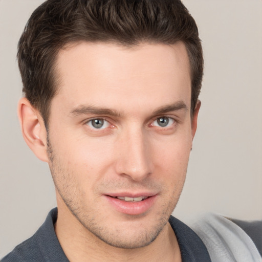 Joyful white young-adult male with short  brown hair and grey eyes