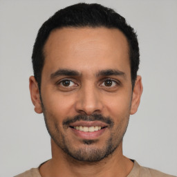 Joyful latino young-adult male with short  black hair and brown eyes