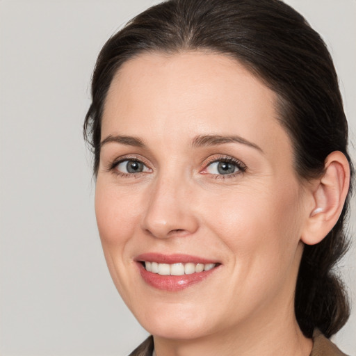 Joyful white adult female with medium  brown hair and grey eyes