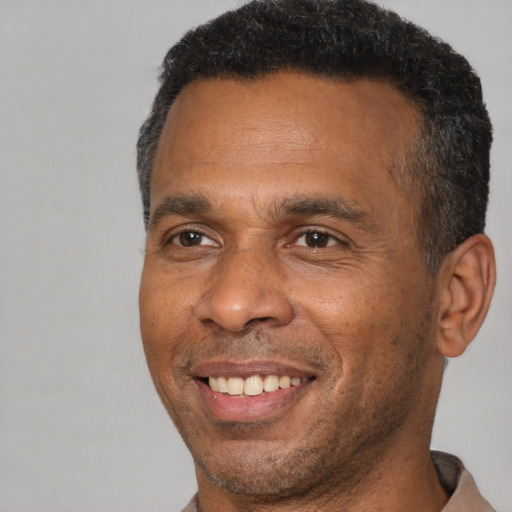 Joyful black adult male with short  brown hair and brown eyes