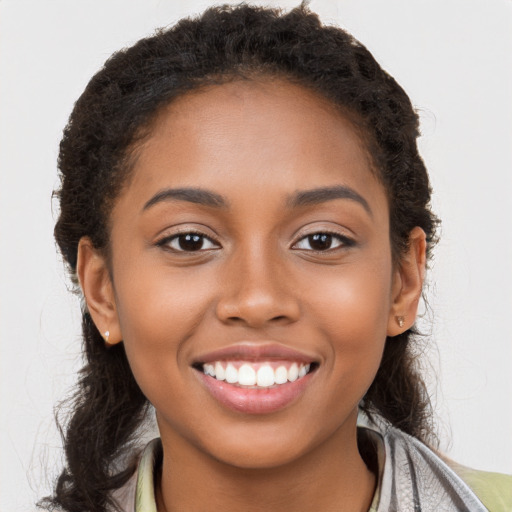 Joyful black young-adult female with long  brown hair and brown eyes
