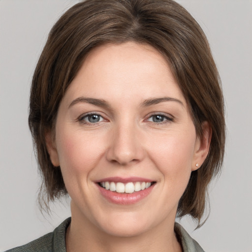 Joyful white young-adult female with medium  brown hair and grey eyes