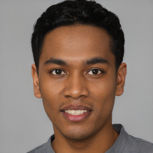Joyful black young-adult male with short  black hair and brown eyes
