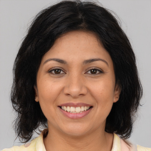 Joyful latino adult female with medium  brown hair and brown eyes