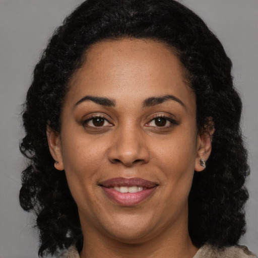Joyful black young-adult female with long  black hair and brown eyes