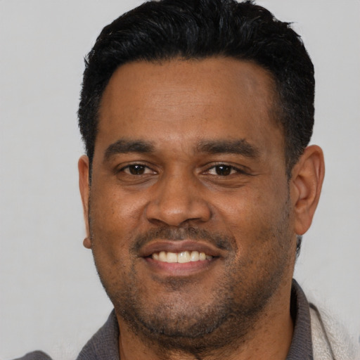 Joyful latino young-adult male with short  black hair and brown eyes