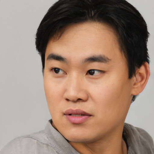 Joyful asian young-adult male with short  black hair and brown eyes