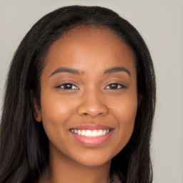 Joyful black young-adult female with long  brown hair and brown eyes