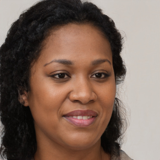 Joyful black young-adult female with long  brown hair and brown eyes