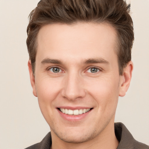 Joyful white young-adult male with short  brown hair and grey eyes