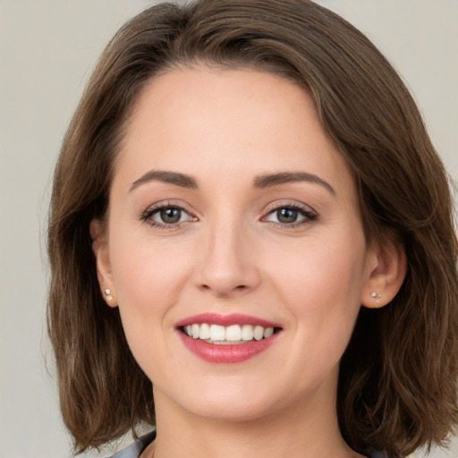 Joyful white young-adult female with medium  brown hair and grey eyes