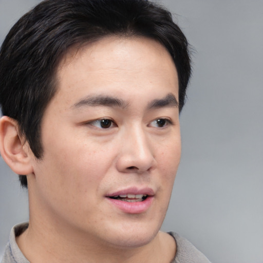 Joyful asian young-adult male with short  brown hair and brown eyes
