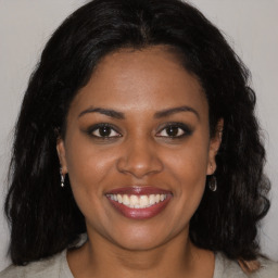 Joyful black young-adult female with long  brown hair and brown eyes