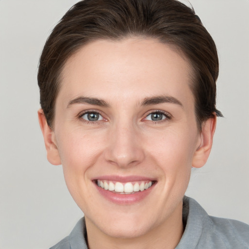 Joyful white young-adult female with short  brown hair and grey eyes