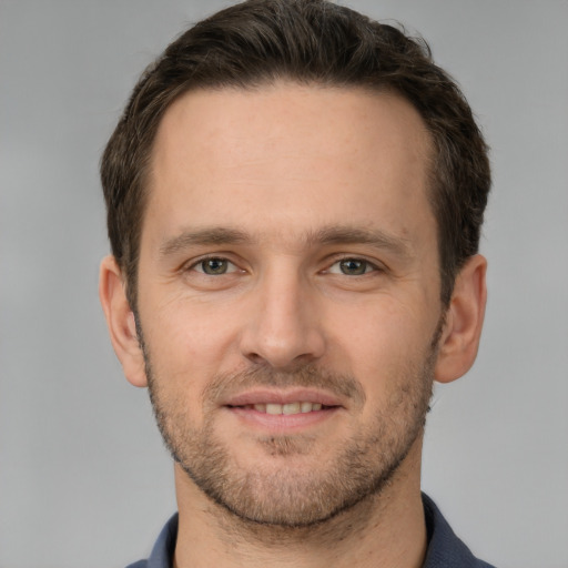 Joyful white young-adult male with short  brown hair and grey eyes