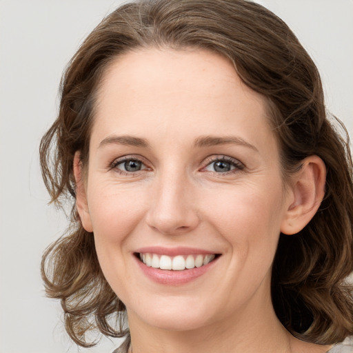 Joyful white young-adult female with long  brown hair and grey eyes