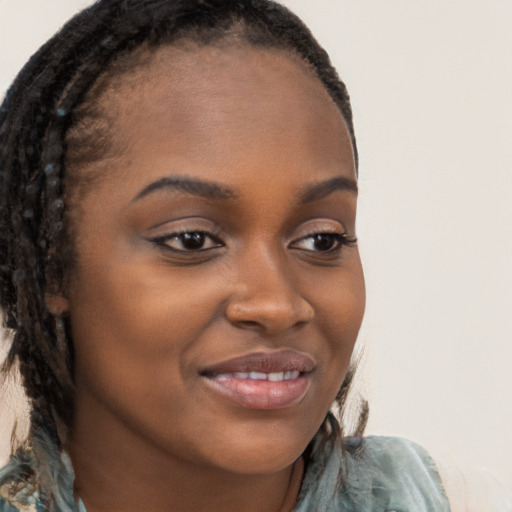 Joyful black young-adult female with long  brown hair and brown eyes