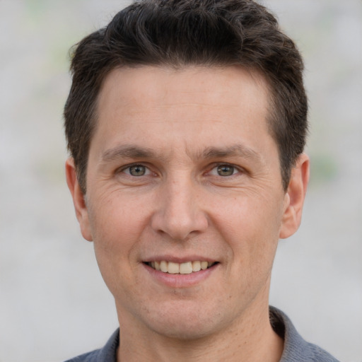 Joyful white adult male with short  brown hair and grey eyes