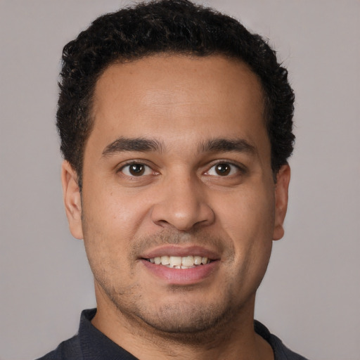 Joyful latino young-adult male with short  brown hair and brown eyes