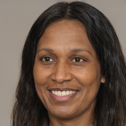 Joyful black adult female with long  brown hair and brown eyes