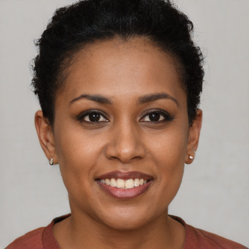 Joyful black young-adult female with short  brown hair and brown eyes