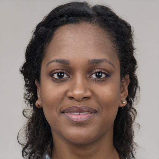Joyful black young-adult female with long  brown hair and brown eyes