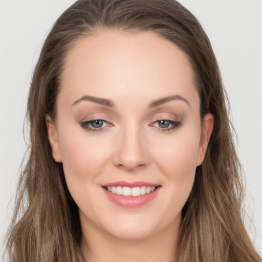 Joyful white young-adult female with long  brown hair and grey eyes