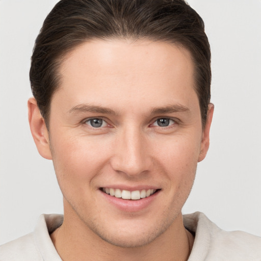 Joyful white young-adult male with short  brown hair and grey eyes