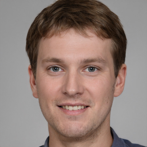 Joyful white young-adult male with short  brown hair and grey eyes