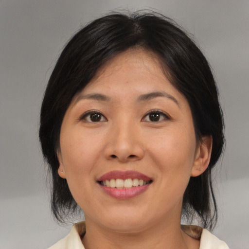 Joyful asian adult female with medium  brown hair and brown eyes