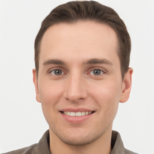 Joyful white young-adult male with short  brown hair and grey eyes