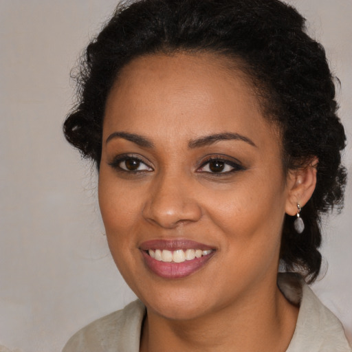 Joyful black young-adult female with long  brown hair and brown eyes