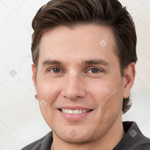 Joyful white young-adult male with short  brown hair and grey eyes