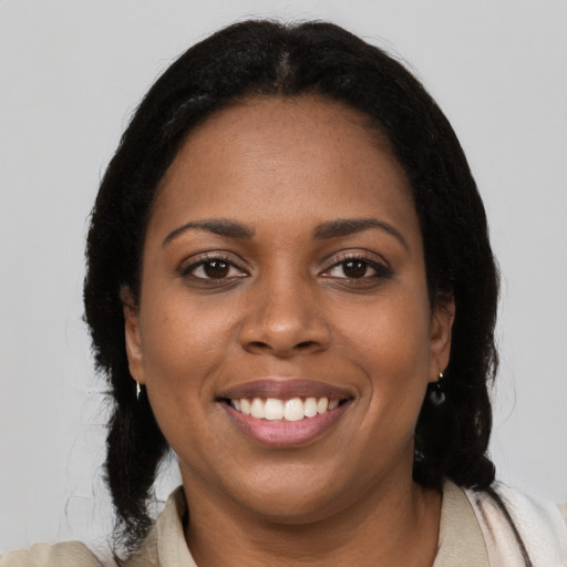 Joyful black young-adult female with long  brown hair and brown eyes