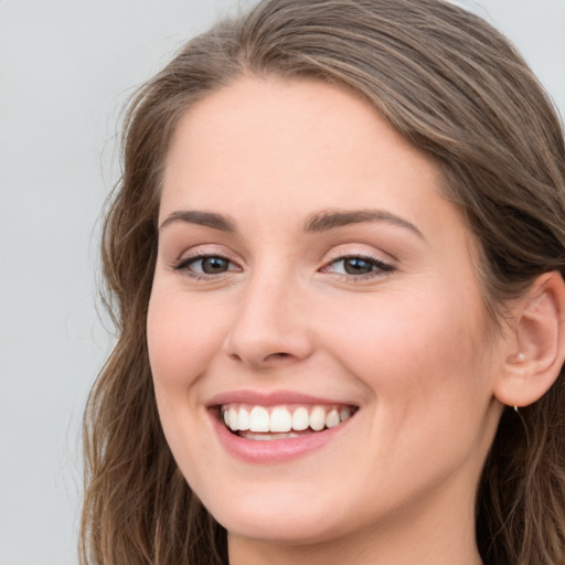 Joyful white young-adult female with long  brown hair and green eyes