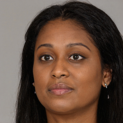 Joyful black young-adult female with long  brown hair and brown eyes